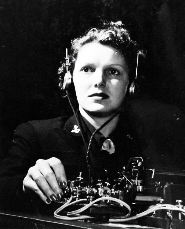 WAVE operator Virginia L. Scott in March 1943, sitting in the Code Room of the U.S. Navy Radio School in Madison, Wisconsin. The photograph, catalogued in the National Archives as 80-G-431533, captures an ordinary phase of the highly technical work carried out by the WAVES during the Second World War. Seeing her at that workstation with her telegraph key, headphones, and operating table.